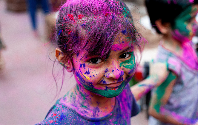 a child in colourful paint at a festival